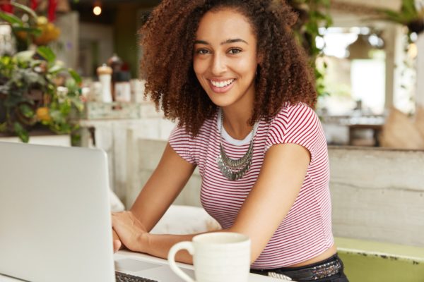 young woman working at laptop having coffee